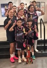 Youth basketball players and coaches posing with trophies